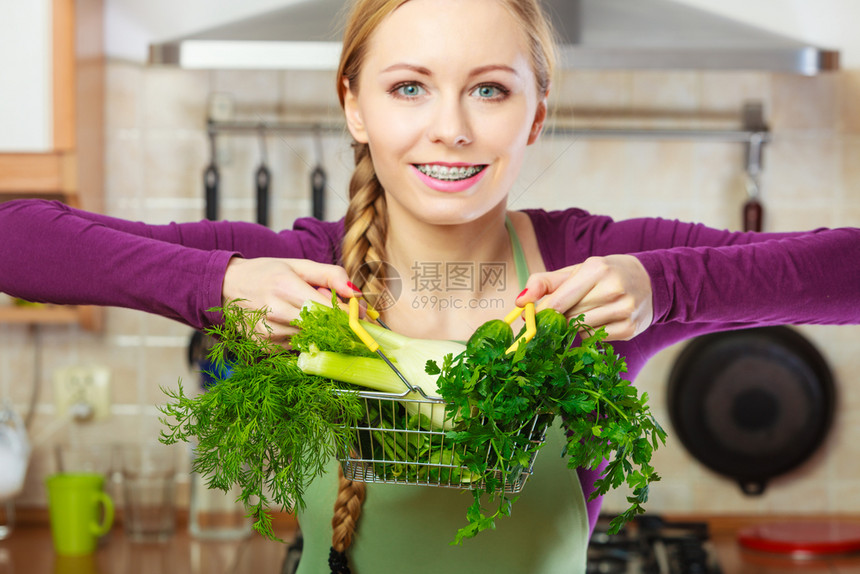 购买健康的饮食品概念厨房里的妇女有许多绿色蔬菜手持小购物篮车里有蔬菜的妇女图片