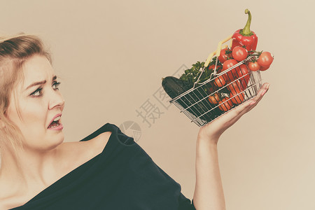 不吃素表情成年妇女不喜欢吃蔬菜健康食品素产小购物篮绿红蔬菜面部不高兴的负表情灰色妇女蔬菜面部负表情背景