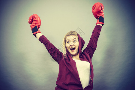 身戴红拳击手套打赢比赛鼓动感到轻松和幸福的运动妇女图片