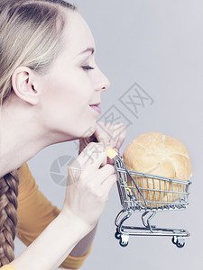妇女拿着小面包手持购物车厢图片