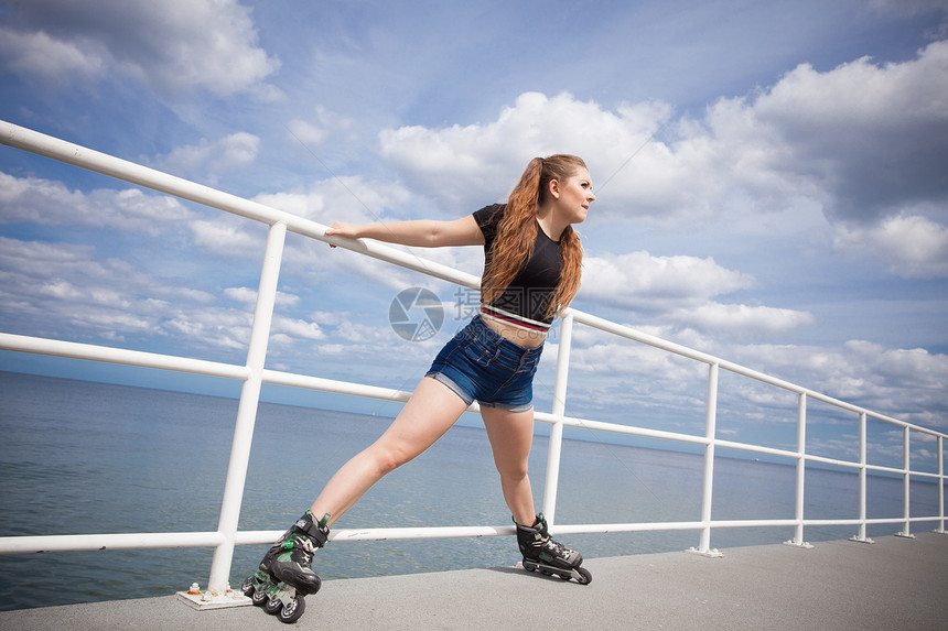 快乐的年轻女子穿着滑雪冰在伸展腿部快乐的年轻女子穿着滚冰鞋快乐的疯狂女子穿着滚冰鞋图片