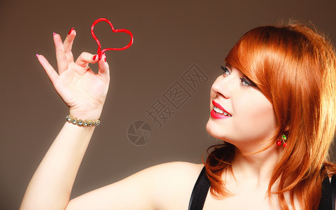 快乐和爱的概念红发女人快乐笑的女孩带着情人节的红心在灰色上情人节图片