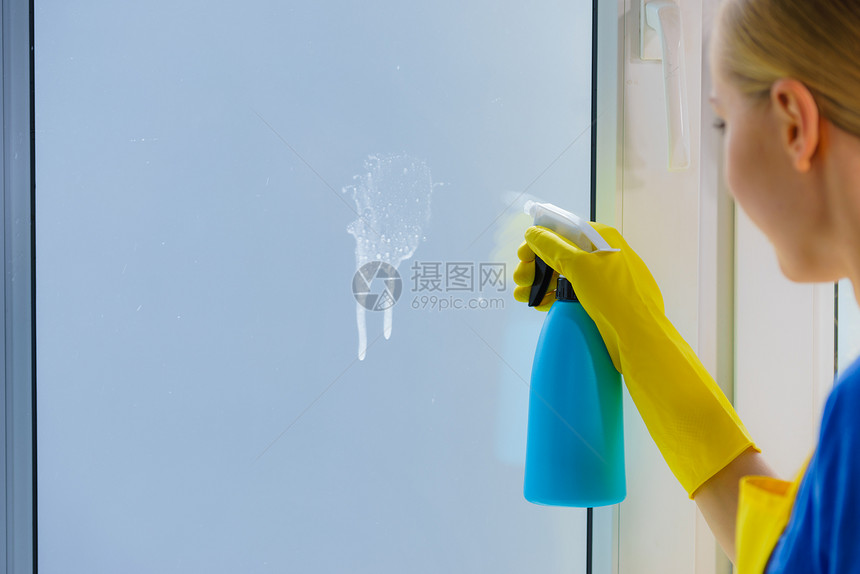 妇女喷洒窗户清洗雾瓶中的洁剂用品家庭护理设备妇女喷洒窗户清洗剂图片