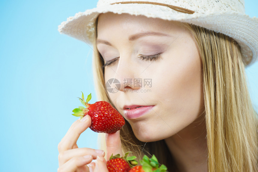 青春女子闭着眼睛闻青蓝鲜草莓水果的香味图片