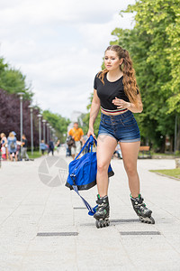 身穿溜冰鞋手持运动袋的青年女子在城里骑马图片