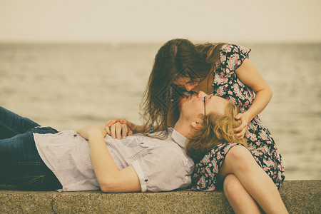 男人躺在女的双腿上享受在海岸线和滨附近的浪漫日子图片