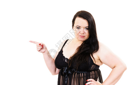 身穿黑蕾丝内衣小圆环的肥胖妇女加上身穿黑色内衣带的身长在复制空间用手指着超重的大胖子模型显示产品在白色上女加内衣尺寸指着复制空间背景图片