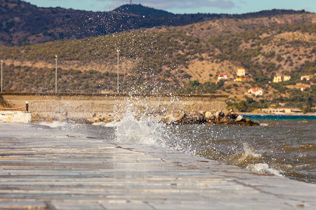 希腊海岸线城镇码头水库墙边缘的海喷洒图片