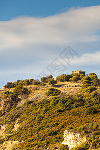 希腊的古语山丘有地中海植物和小城堡的型灌木丛与云端的天空相对抗图片