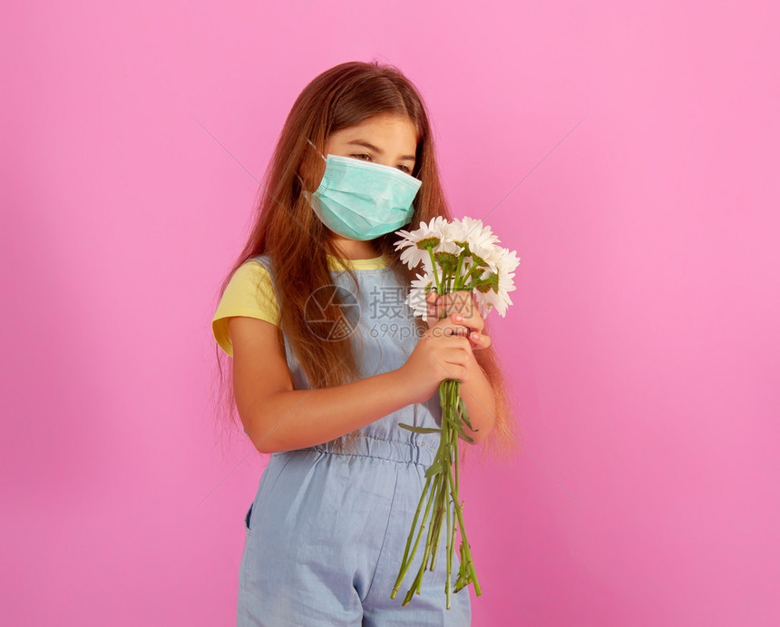 有过敏的小女孩穿着医用面罩花朵的过敏小姑娘带着温柔粉红背景的花束图片