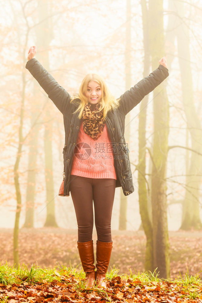 快乐的女子在雾一天走来放松在浪漫的秋天森林公园露图片