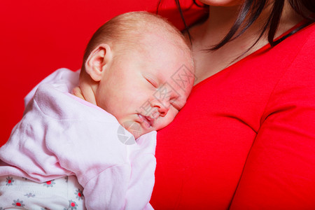家庭童年和育儿概念婴在母亲胸前睡觉红背景图片