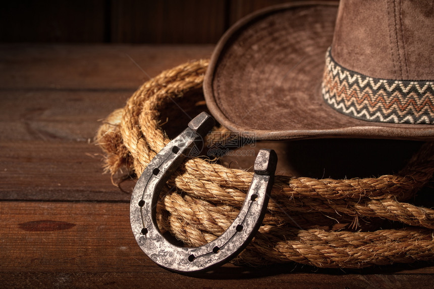 古老的马蹄铁就在经典牛仔帽和黑色木头背景的拉索旁边图片
