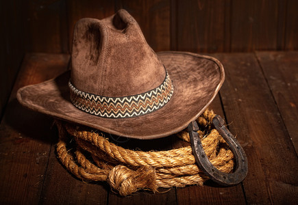 马蹄形古老的马蹄铁就在经典牛仔帽和黑色木头背景的拉索旁边背景