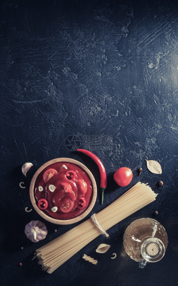 碗里加番茄酱和黑背景表格纹理上的意大利面酱最高视图图片