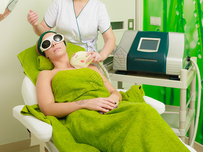 妇女戴安全眼镜在美容师的乳沟上接受激光治疗图片