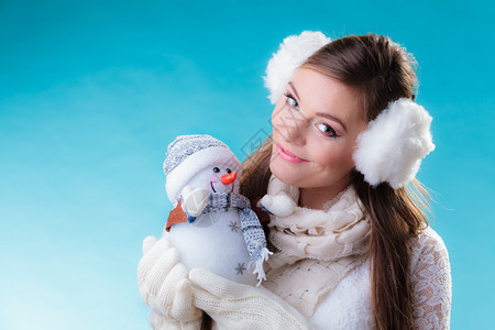 穿着温暖衣服的年轻女孩带着快乐的雪人玩具图片