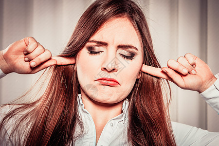 眼睛耳朵年轻有压力的女处理情绪时会遮住耳朵偏头痛的女在办公室里可以避免噪音闭着眼睛的紧张女用手指塞住耳朵背景