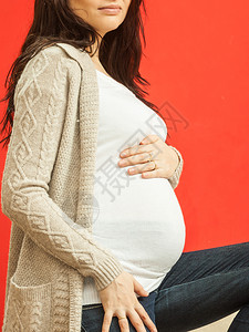 孕妇露出肚子在红色背景上图片