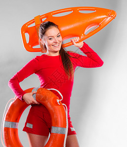预防事故和救水年轻女在值勤时微笑的女救生员将设备放在灰色上图片