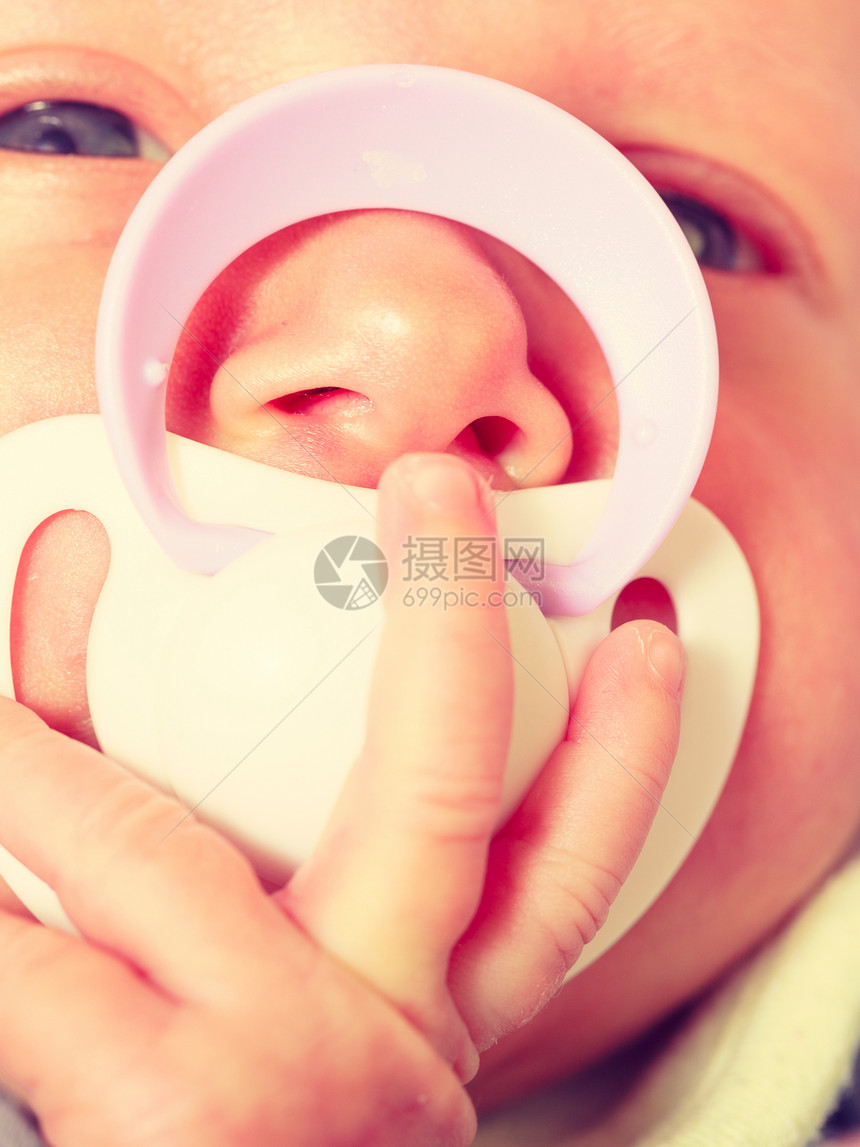婴儿护理童年概念的美丽小新生婴儿平静地躺在床上嘴里塞着小茶叶闭合图片
