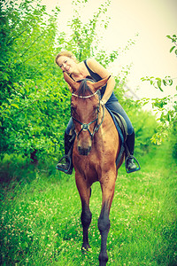 年轻女人坐在马背上靠着它拥抱和倾斜出家门的年轻女人图片
