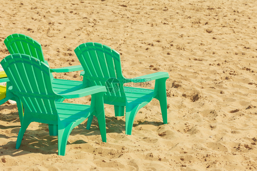 沙滩上三张绿色塑料椅阳光明媚的沙滩上放轻松地方沙滩上绿色塑料椅图片