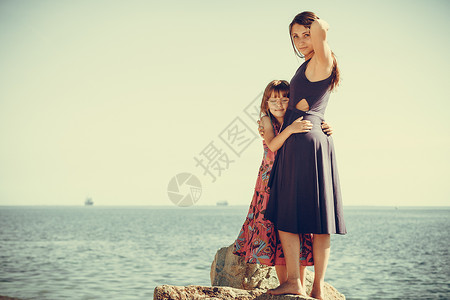 母亲和女儿在海面岩石上摆姿势图片