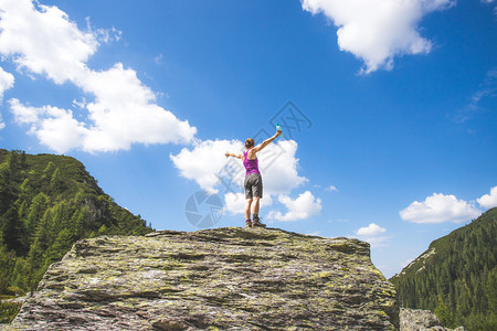 目标实现运动女孩站在一块大岩石上举起双手图片