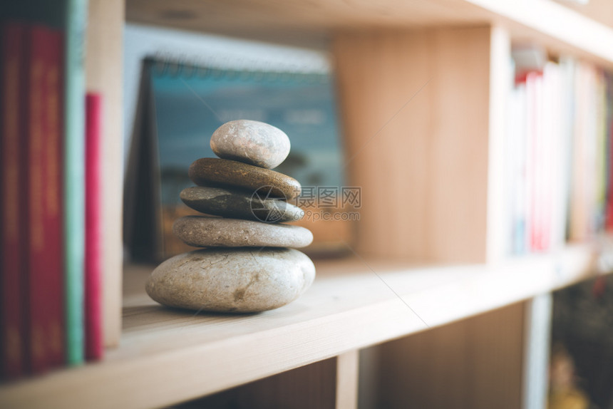 风水在书架上家里的石棺表面和背景的模糊书籍平衡与放松阳光图片