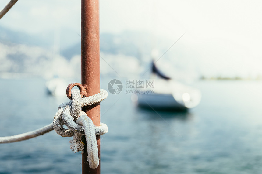 在前景暗的木码头上行驶绳索在模糊背景的帆船上行驶图片