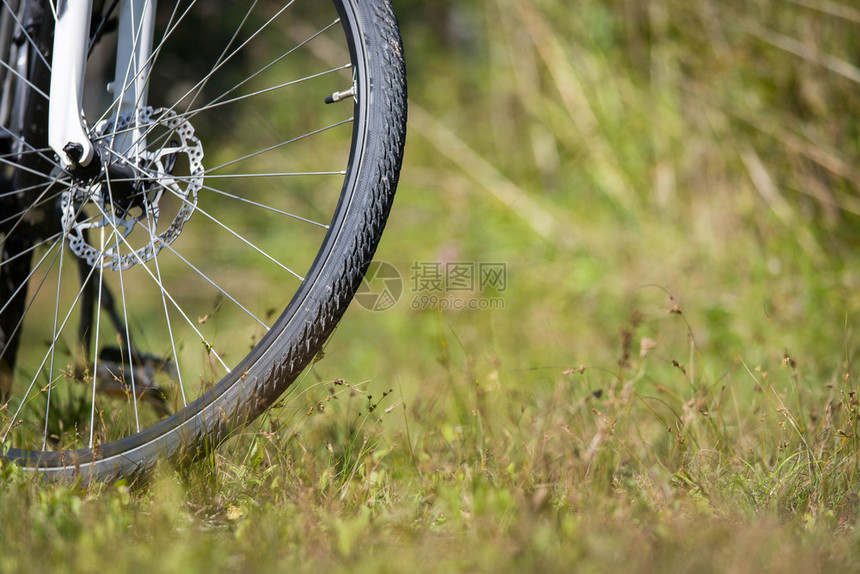 停放在草地上自行车的前轮特写图片