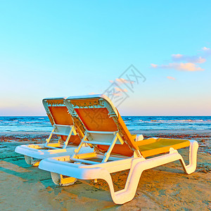 沙滩上两张空甲板椅图片