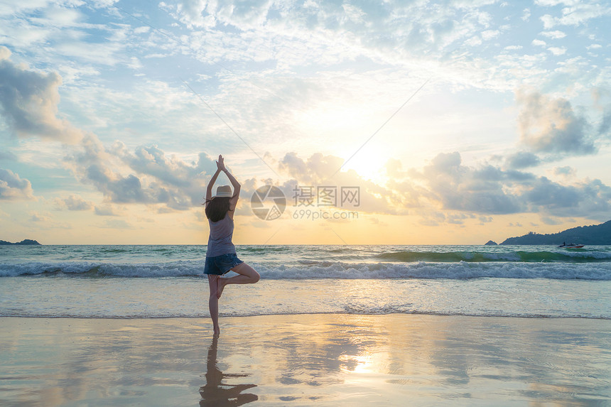 快乐的亚洲女在海滩上做瑜伽或锻炼图片
