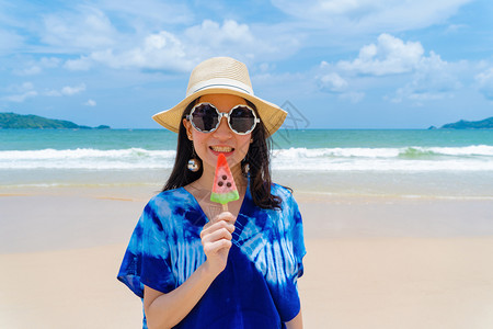 在泰国普吉中午的海洋或自然外度假期间在海滩吃西瓜冰淇淋的亚洲快乐妇女图片