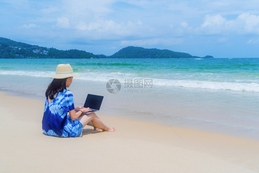 在泰国普吉中午的海洋或自然旅行度假室外时在海滩使用电脑笔记本的亚洲快乐妇女图片