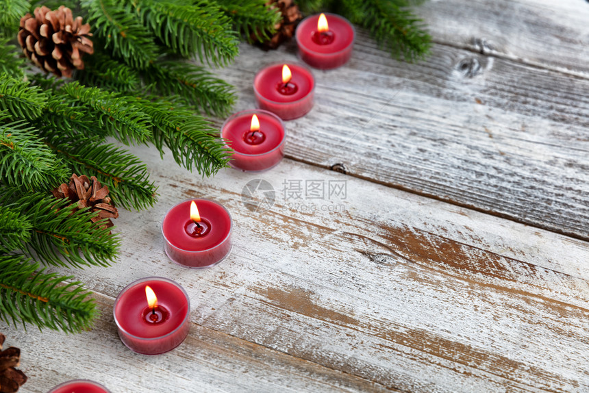 传统的圣诞节蜡烛和长绿树枝有白色生木背景图片