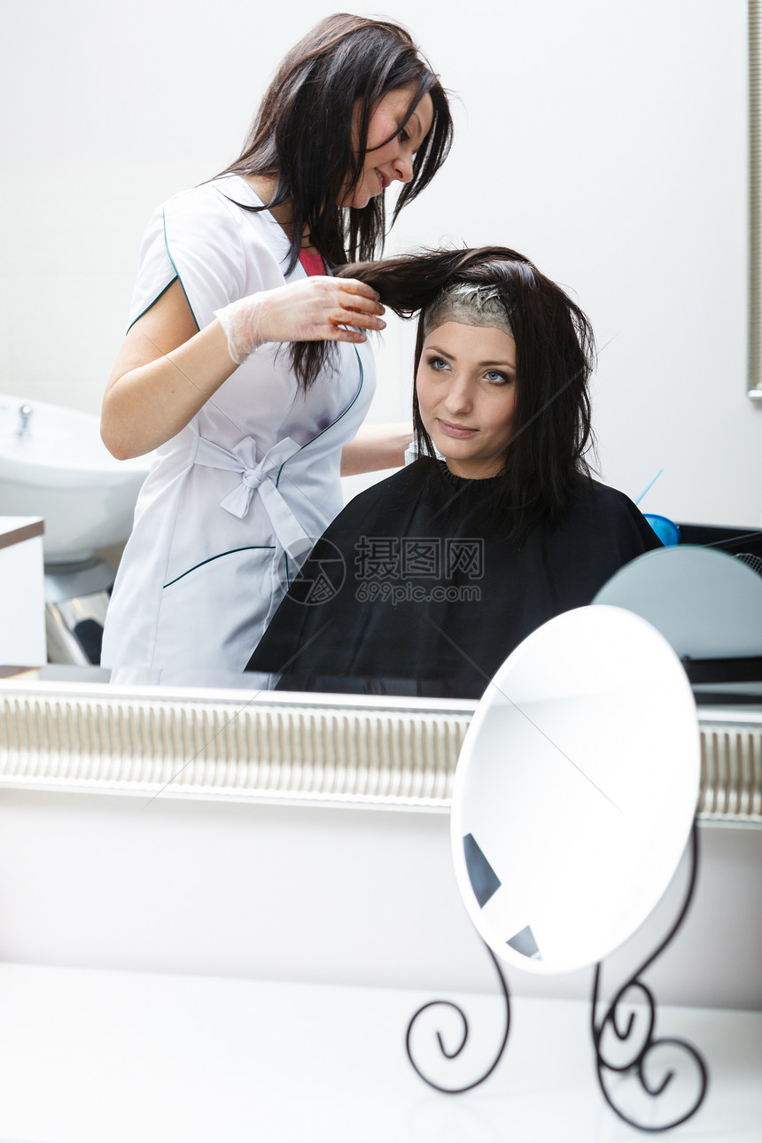 穿着黑斗篷的女子在美容院发师染上她的头发图片