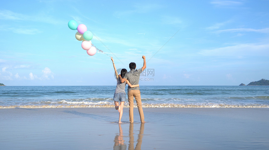 快乐的亚洲情侣在泰国普吉Phucket中午的海洋或自然度假室外旅行时在海滩上持有彩色气球图片