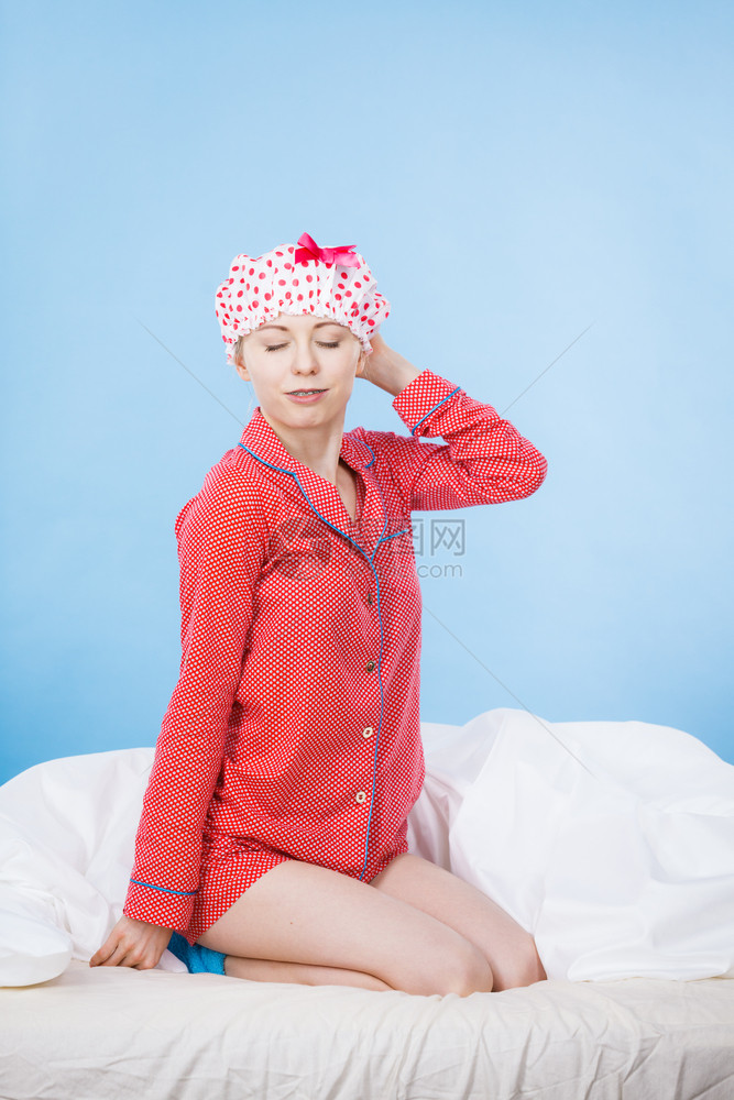 穿着粉红色睡衣和圆顶浴帽坐在床上洗澡后图片
