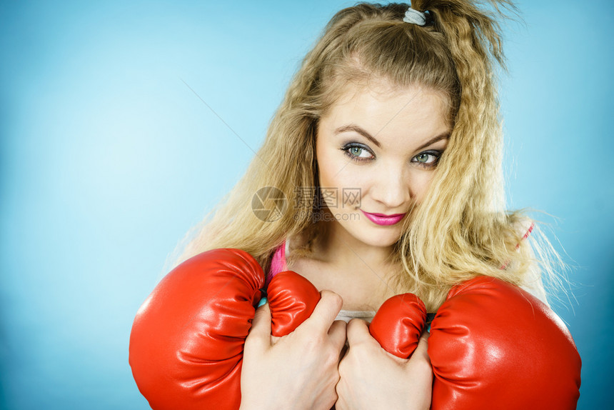 可爱的金发美女拳击手 带着大有趣的红色手套 玩运动拳击工作室 蓝射击滑稽的红手套女孩 玩运动拳击图片