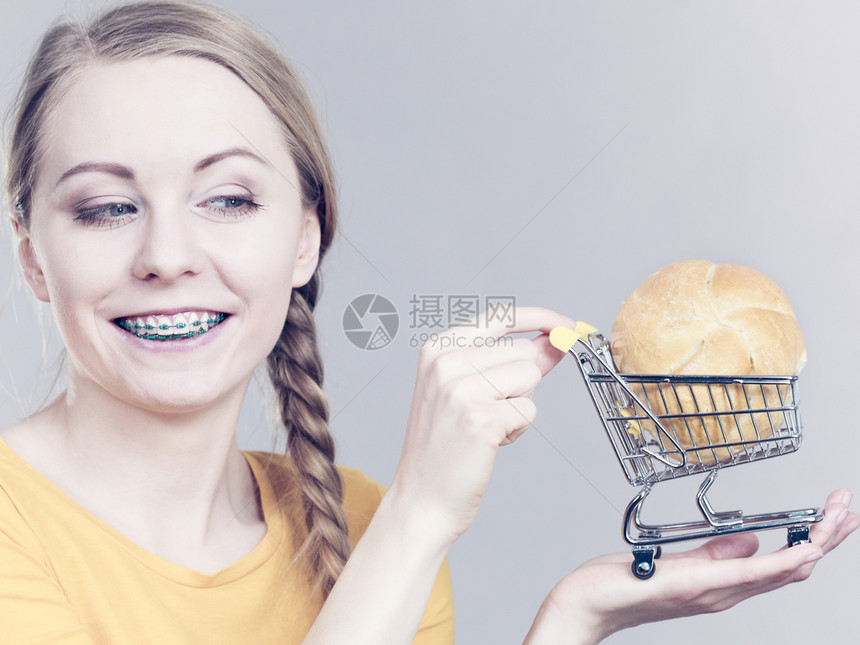 妇女拿着小面包手持购物车厢图片
