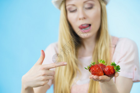 青春女子露出新鲜草莓水果用蓝唇舔嘴健康饮食女孩露出新鲜草莓背景图片