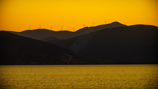 日落时山力发电站风涡轮机景海希腊可再生态能源概念日落时风力涡轮机海景图片