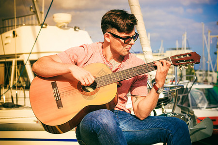 年轻时尚男子穿着太阳眼镜在户外弹经典吉他夏天时间图片