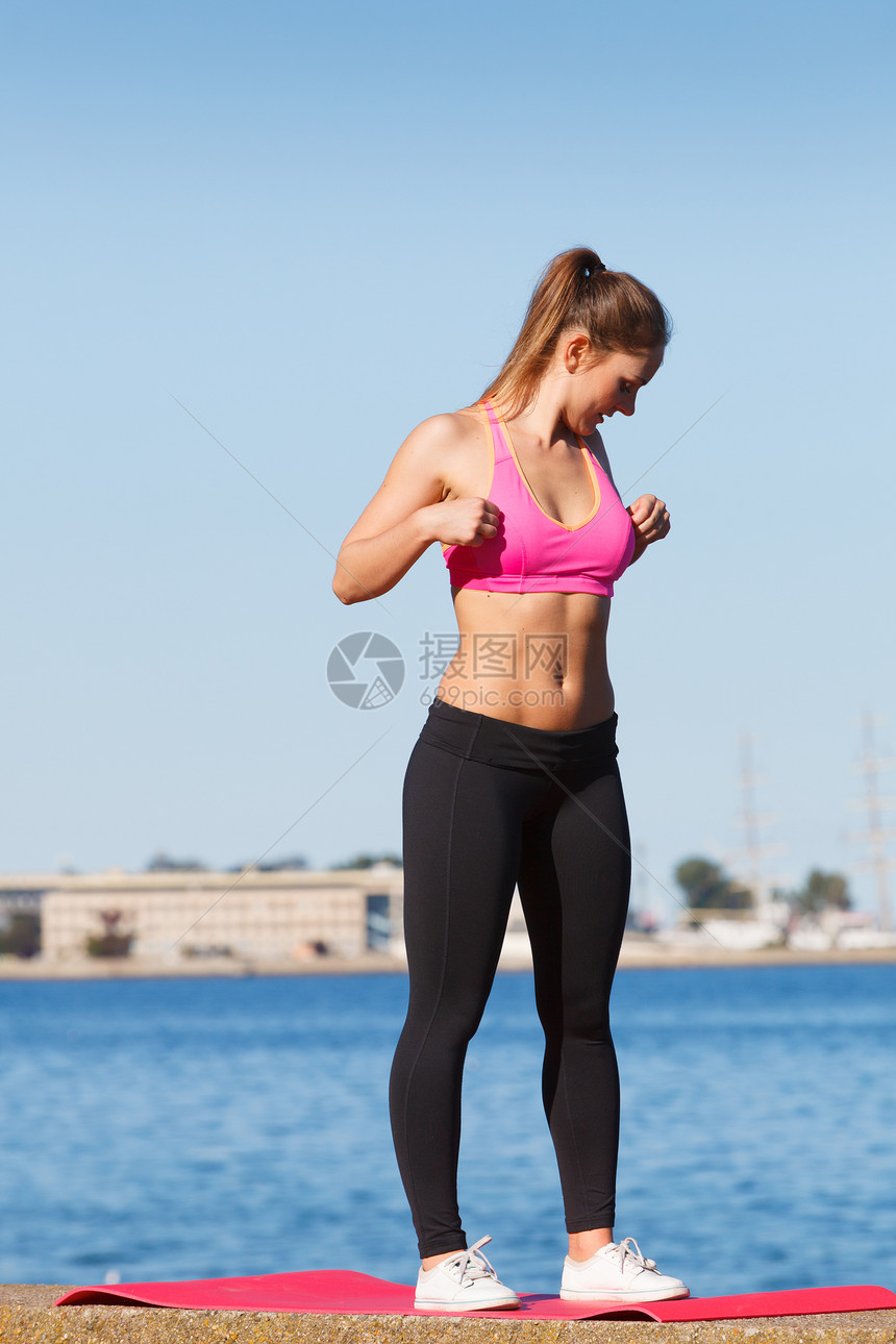 外出放松运动翼概念运动服上的妇女运动服前在海边的堤坝上站着运动前的伸展海上的堤坝妇女运动图片