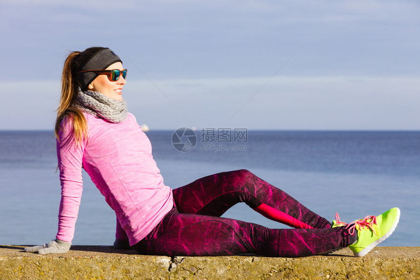 女子在户外运动后休息健身女运动员在寒冷的天气中穿着温暖运动服在海边休息女子在寒冷的户外运动后休息图片