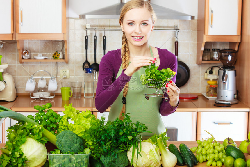 购买健康的饮食品概念厨房里的妇女有许多绿色蔬菜手持小购物篮车厨房里的妇女手持蔬菜篮子厨房里的妇女手持蔬菜篮子图片