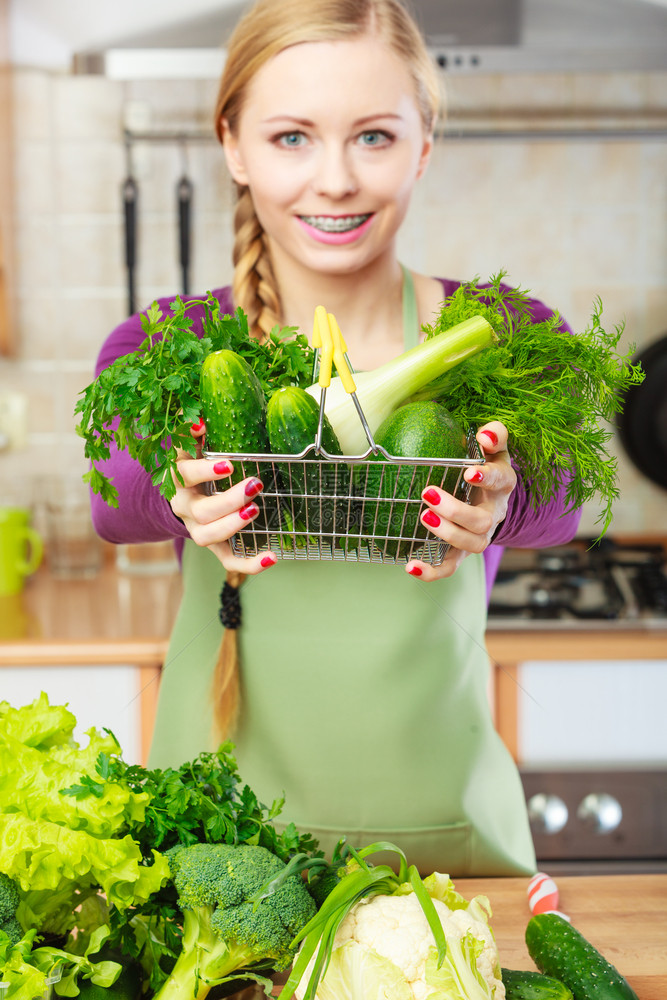 购买健康的饮食品概念厨房里的妇女有许多绿色蔬菜手持小购物篮厨房里的妇女手持蔬菜厨房里的妇女手持蔬菜篮子图片