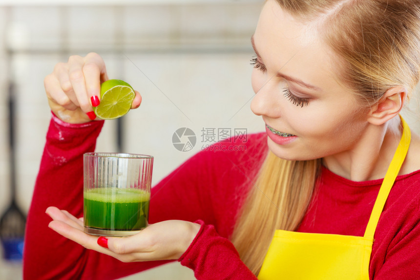 厨房里的年轻女子拿着绿色健康的蔬菜冰凉果汁杯子厨房里的女人拿着蔬菜冰凉果汁图片